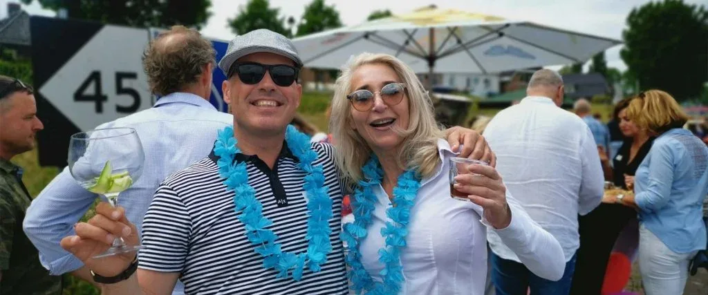 Leden van Elkaar Ontmoeten met bloemenkransen op een zomers evenement